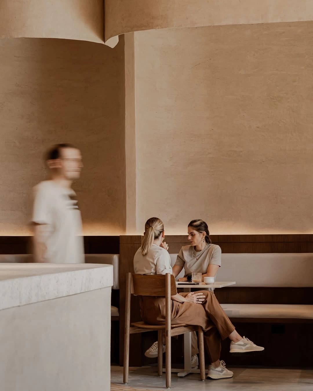 Two people at a café table, the world moving around them