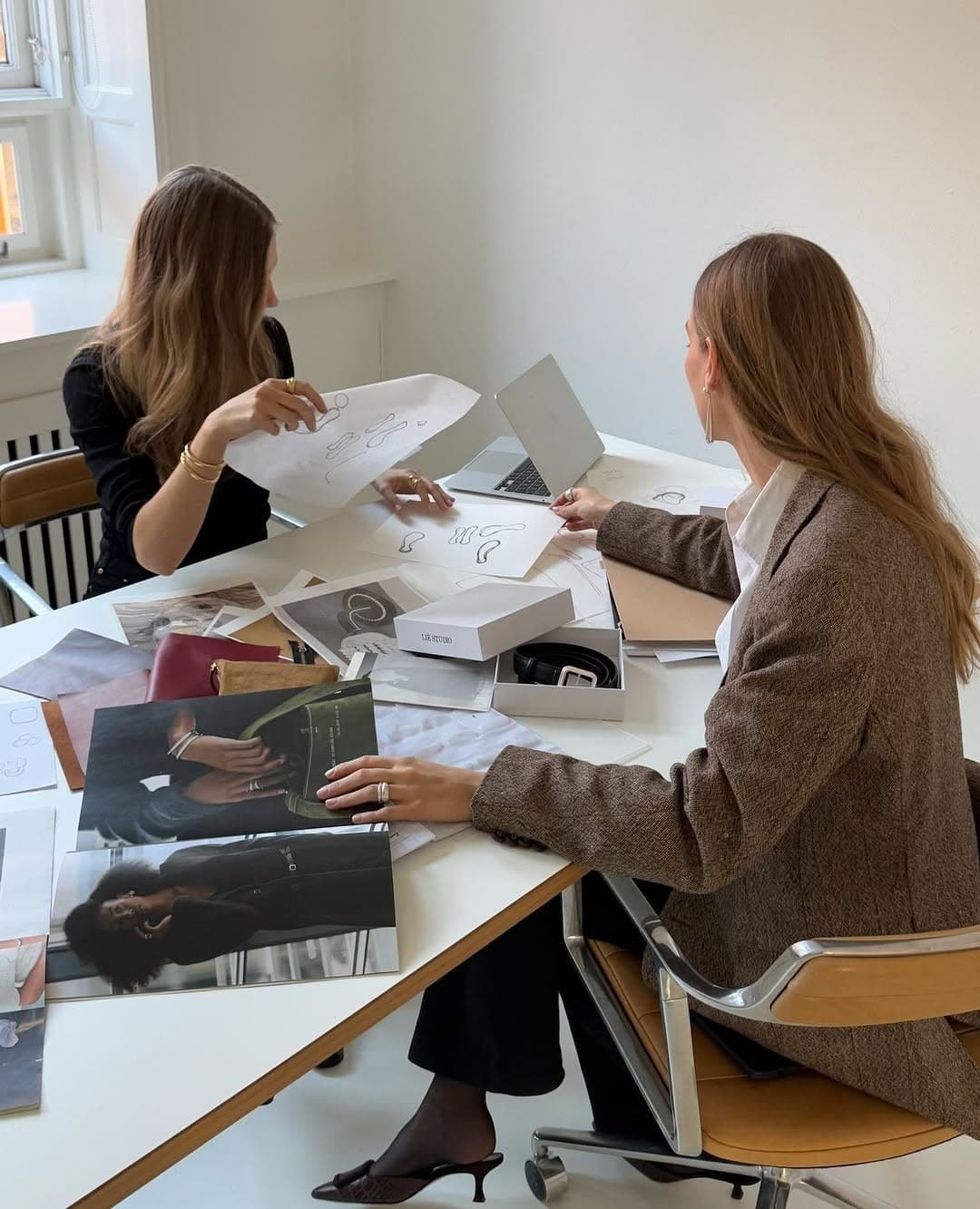 Two colleagues working through pages spread across a desk
